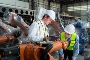 Both of engineers working together in a robotic arm factory, Robotic arm industry and engineering concept. photo