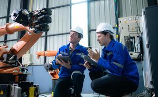 Engineer and technician working with robot arm in factory. Industry and engineering concept. photo