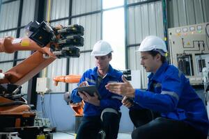 Engineer and technician working with robot arm in factory. Industry and engineering concept. photo