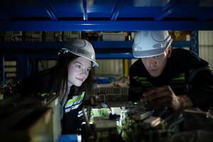 A young female engineer and a male supervisor work together in robotic arm spare parts warehouse, Robotic arm industry and engineering concept. photo