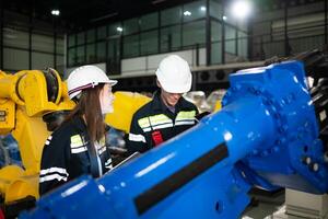 ambos de ingenieros trabajando juntos en un robótico brazo fábrica, robótico brazo industria y Ingenieria concepto. foto