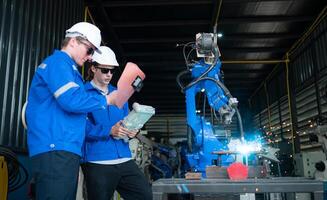 Industrial workers working with robotic arm welding machine in factory, Robotic arm welding industry and engineering concept. photo