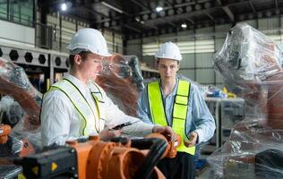 Both of engineers working together in a robotic arm factory, Robotic arm industry and engineering concept. photo