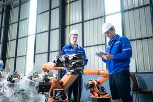 Engineer and technician working with robot arm in factory. Industry and engineering concept. photo