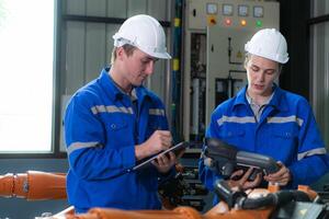 Engineer and technician working with robot arm in factory. Industry and engineering concept. photo