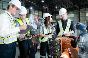 Group of engineers and technicians working together in a robotic arm factory. Inspecting robot arm before delivering to customers photo