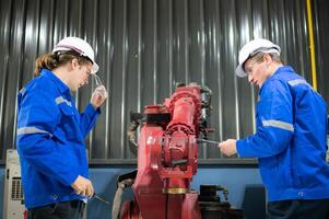 ambos de ingenieros trabajando juntos en un robótico brazo fábrica, robótico brazo industria y Ingenieria concepto. foto