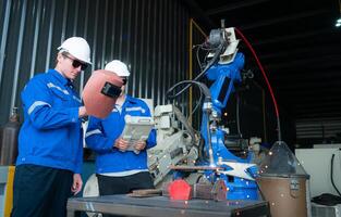 Industrial workers working with robotic arm welding machine in factory, Robotic arm welding industry and engineering concept. photo