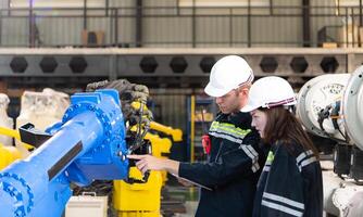 ambos de ingenieros trabajando juntos en un robótico brazo fábrica, robótico brazo industria y Ingenieria concepto. foto