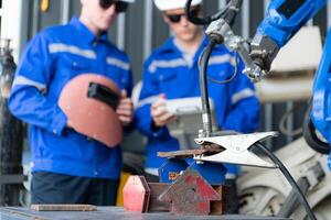 Industrial workers working with robotic arm welding machine in factory, Robotic arm welding industry and engineering concept. photo
