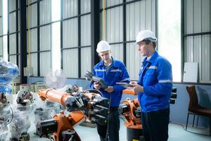 Engineer and technician working with robot arm in factory. Industry and engineering concept. photo