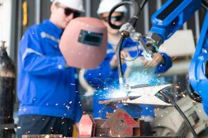 Industrial workers working with robotic arm welding machine in factory, Robotic arm welding industry and engineering concept. photo