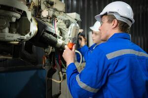 ambos de ingenieros trabajando juntos en un robótico brazo fábrica, robótico brazo industria y Ingenieria concepto. foto