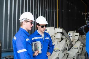 Industrial workers working with robotic arm welding machine in factory, Robotic arm welding industry and engineering concept. photo