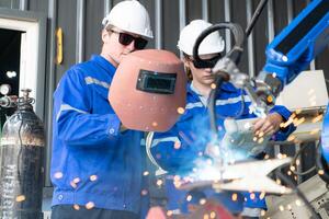 Industrial workers working with robotic arm welding machine in factory, Robotic arm welding industry and engineering concept. photo