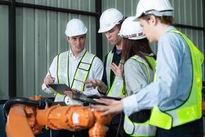 Group of engineers and technicians working together in a robotic arm factory. Inspecting robot arm before delivering to customers photo