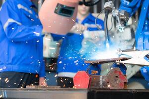 Industrial workers working with robotic arm welding machine in factory, Robotic arm welding industry and engineering concept. photo
