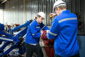 ambos de ingenieros trabajando juntos en un robótico brazo fábrica, robótico brazo industria y Ingenieria concepto. foto