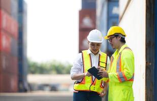 Portrait of Asian woman engineer and worker working with co-worker at overseas shipping container yard. photo