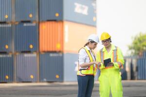 Portrait of Asian woman engineer and worker working with co-worker at overseas shipping container yard. photo