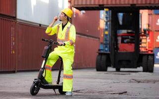 retrato de un almacén trabajador Hablando en un walkie película sonora con un compañero de trabajo en un vacío envase almacén mientras conducción un scooter a inspeccionar trabajo foto