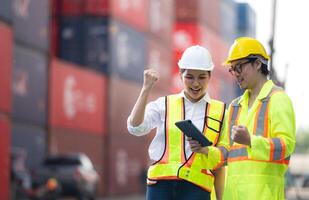 Portrait of Asian woman engineer and worker working with co-worker at overseas shipping container yard. photo
