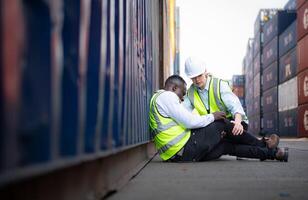 A guy worker was involved in a leg accident in a container storage yard. A colleague was using the walkie talkie to request immediate aid. photo