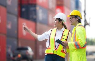 Portrait of Asian woman engineer and worker working with co-worker at overseas shipping container yard. photo