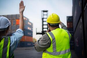 Group of workers in the import and export industry use walkie talkies to communicate with drivers of reach stacker containers in an empty container warehouse. photo