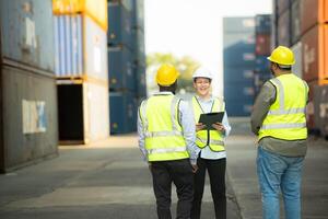 Group of engineers working with laptop in the container yard. This is a freight transportation and distribution warehouse. photo