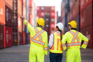 Group of engineers working with laptop in the container yard. This is a freight transportation and distribution warehouse. photo