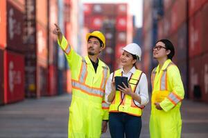 Group of engineers working with laptop in the container yard. This is a freight transportation and distribution warehouse. photo