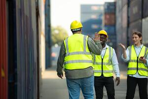 Group of workers in a container storage yard greeting each other during breaks in front of container warehouse, photo