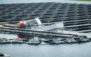 técnico actualmente evaluando y reparando el transmisión terminales para electricidad generado por solar energía en un flotante solar poder sistema. foto