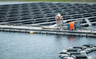 Both of technicians are currently evaluating and repairing the transmission terminals for electricity generated by solar energy in a floating solar power system. photo