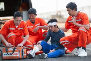 el paramédico es ayudando un lesionado hombre en un emergencia situación en el la carretera. foto