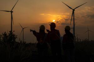 Silhouette of group engineers and windmills on the background of the setting sun photo