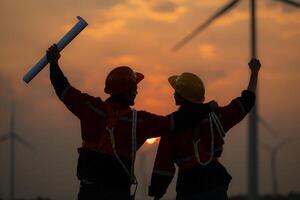 Silhouette of engineer and technician with a wind farm and sunset background photo