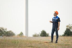 Engineer working in wind turbine farm with blue sky background photo