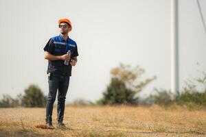 Engineer working in wind turbine farm with blue sky background photo