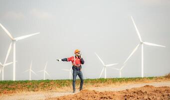 Engineer working in wind turbine farm with blue sky background photo