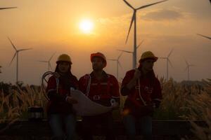 Silhouette of group engineers and windmills on the background of the setting sun photo