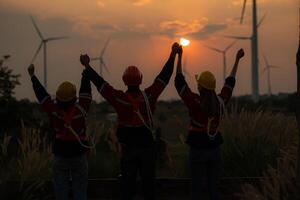 Silhouette of group engineers and windmills on the background of the setting sun photo