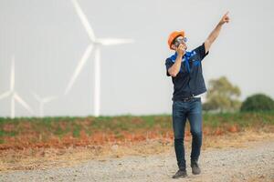 Engineer working in wind turbine farm with blue sky background photo