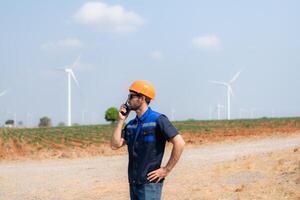 Engineer working in wind turbine farm with blue sky background photo
