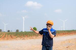 Engineer working in wind turbine farm with blue sky background photo