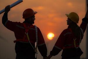 Silhouette of engineer and technician with a wind farm and sunset background photo