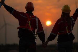 Silhouette of engineer and technician with a wind farm and sunset background photo