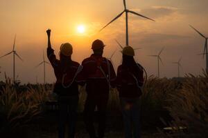 Silhouette of group engineers and windmills on the background of the setting sun photo