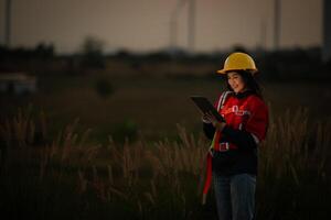 Portrait of a beautiful asian woman engineer working with laptop in wind turbine field photo